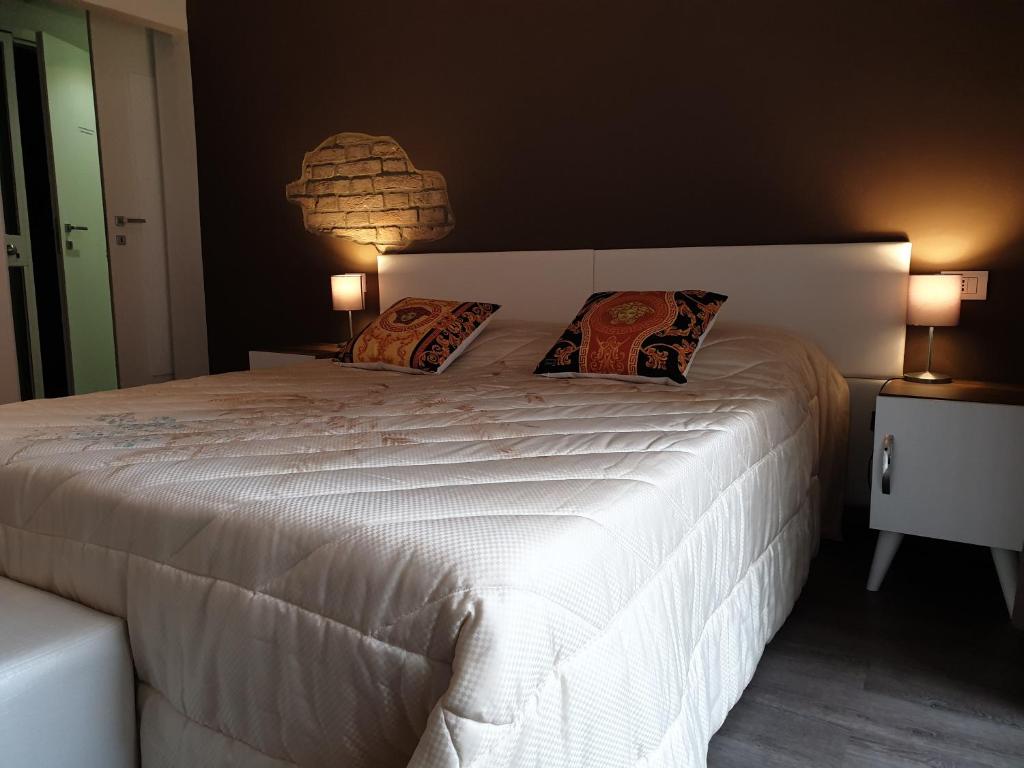 una camera da letto con un grande letto bianco con due cuscini di ForumGuestHouse Center Parking a Parma