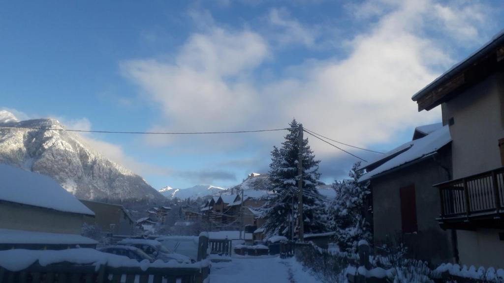 a village covered in snow with a tree and mountains at Le Bacchu Ber in Briançon