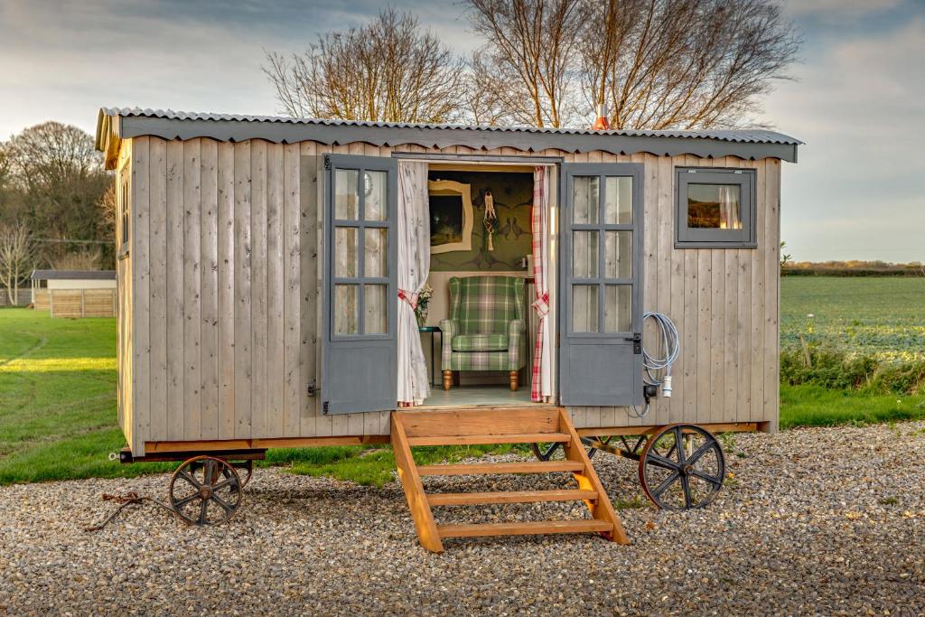 una casa pequeña sobre ruedas con una silla en la puerta en The Covey en Felbrigg