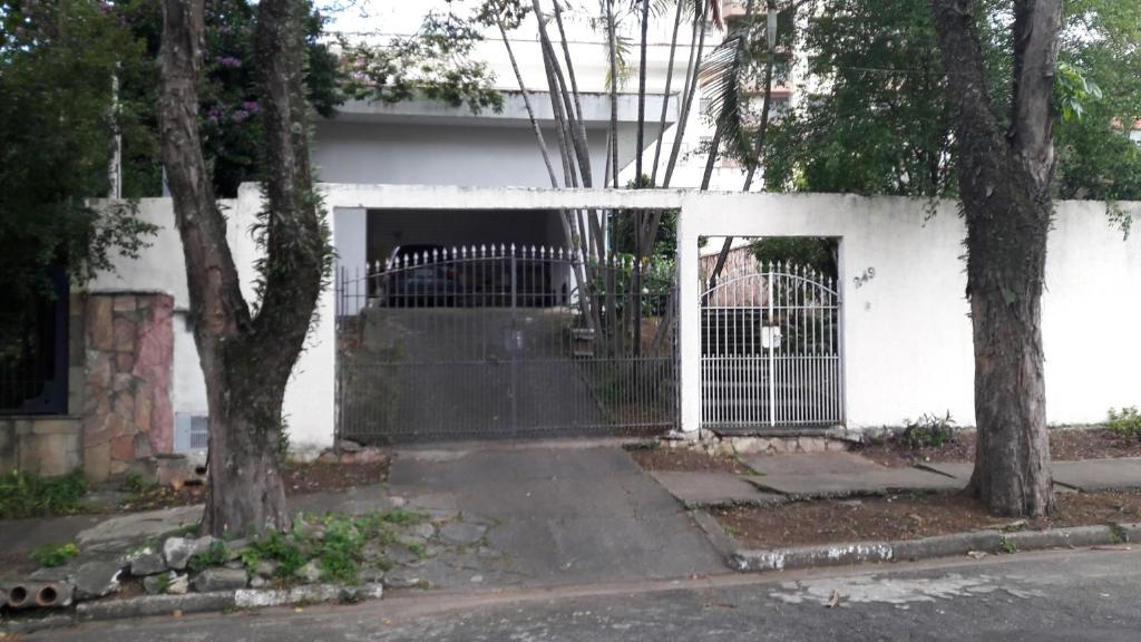 Uma casa branca com um portão à frente. em JASMIM em São Paulo