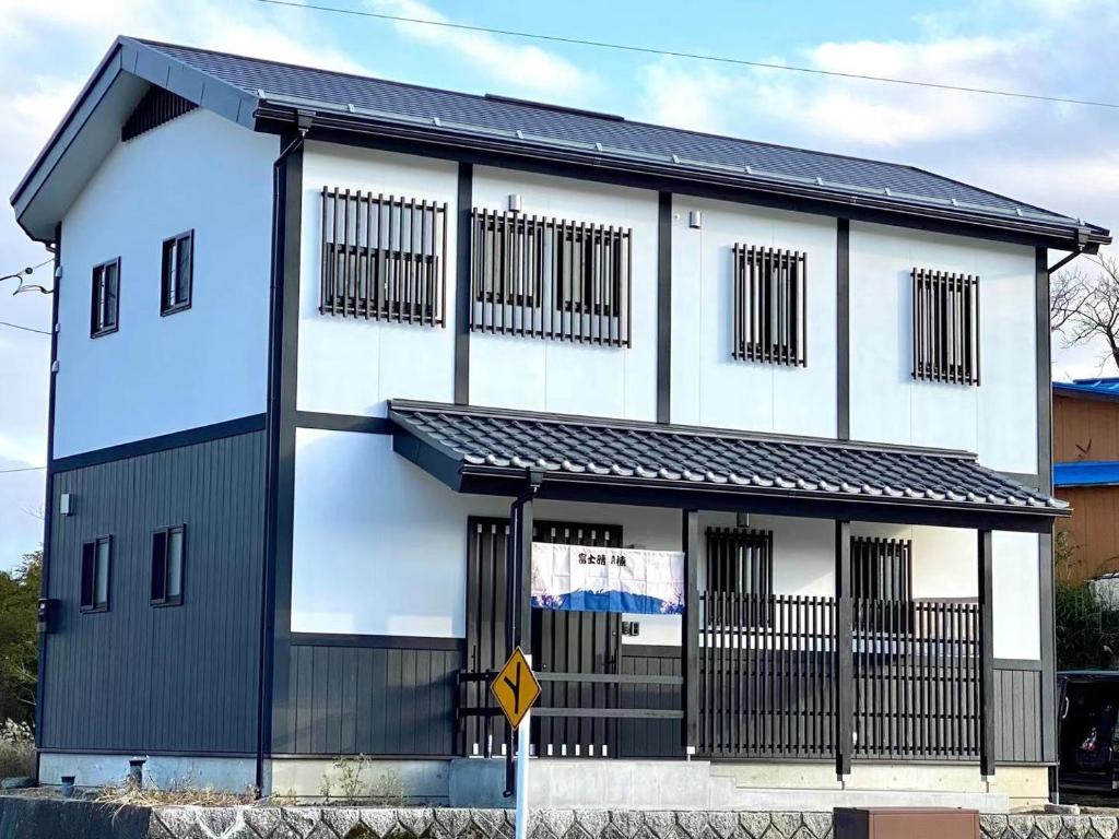 ein weißes und schwarzes Gebäude mit einem Schild davor in der Unterkunft 富士晴 Guest House in Minamitsuru