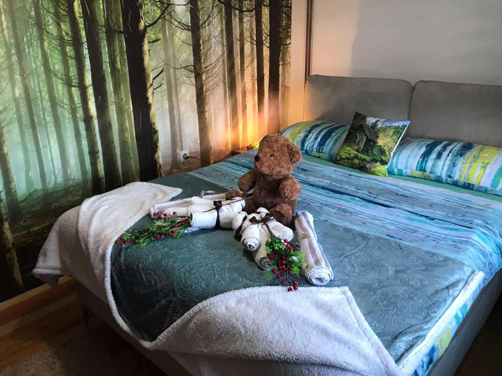 a teddy bear sitting on top of a bed at Apartmani NINA Zlatar in Nova Varoš