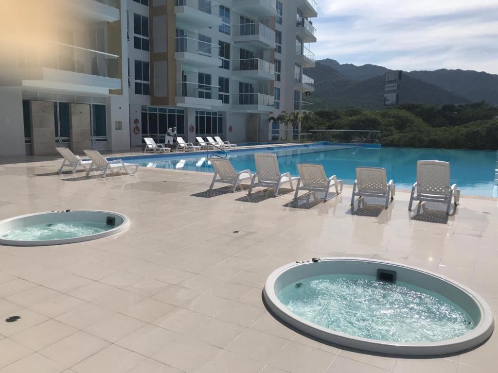a swimming pool with lounge chairs and a building at Hermoso Apto con vista a la sierra y a Cabo Tortuga en el sector del Irotama en Santa Marta in Gaira
