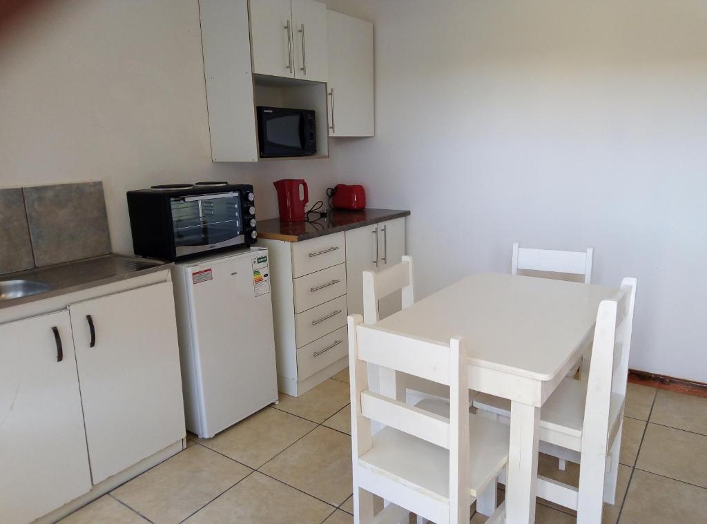 a small kitchen with a white table and a microwave at Spacious 1bed + braai 13km to Paternoster beach in Vredenburg
