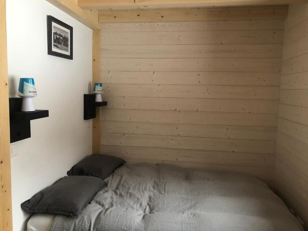 Cama en habitación con pared de madera en Gaspoz en Morgins