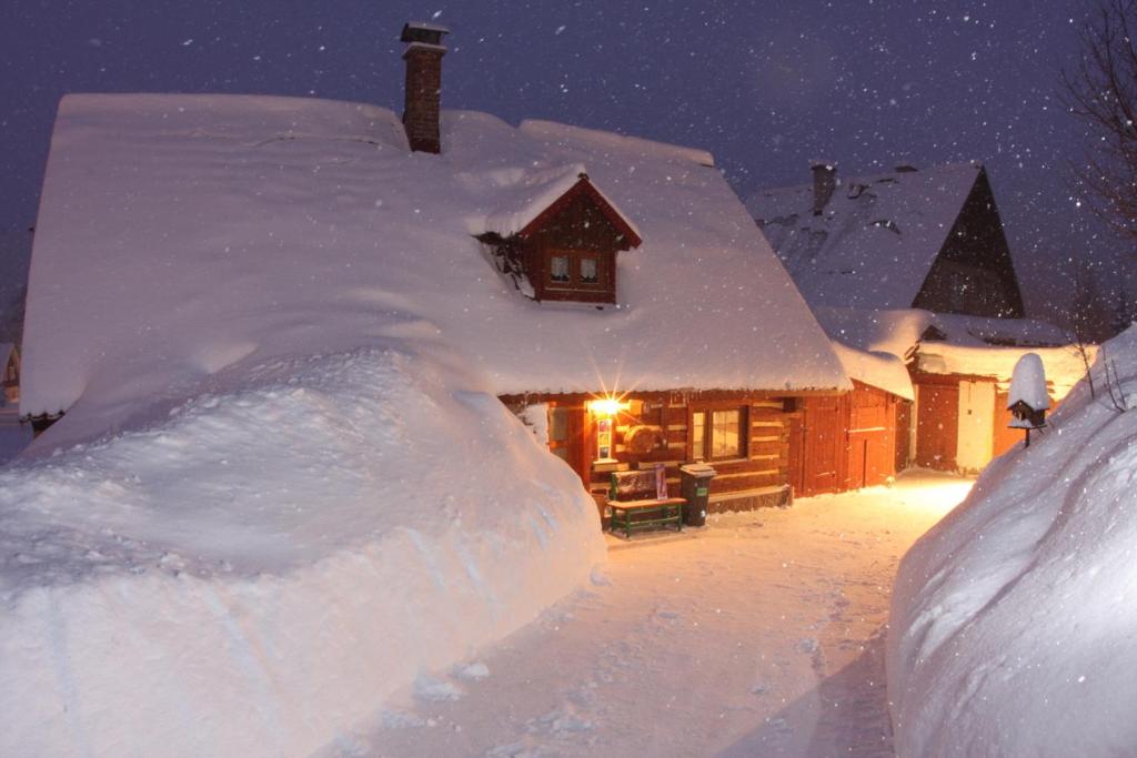 Chaloupka Harrachov في هاراشوف: منزل مغطى بالثلج مع كومة من الثلج