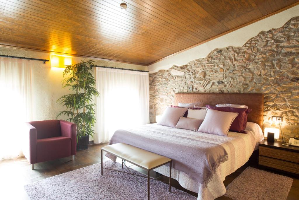 - une chambre avec un grand lit et un mur en pierre dans l'établissement Cal Barber, à Botarell