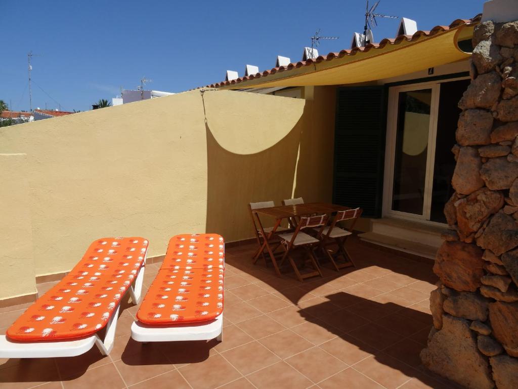 Apartamento las Siete Palmeras في كالا إن بلانيس: مقعد برتقالي وبيض وطاولة على الفناء