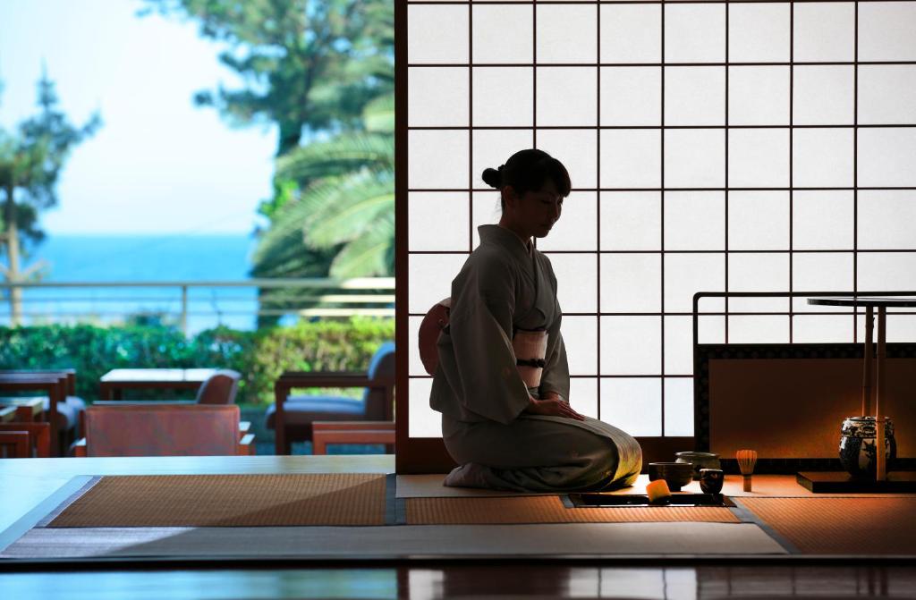 
a man sitting on a bench in front of a window at Imaiso in Kawazu
