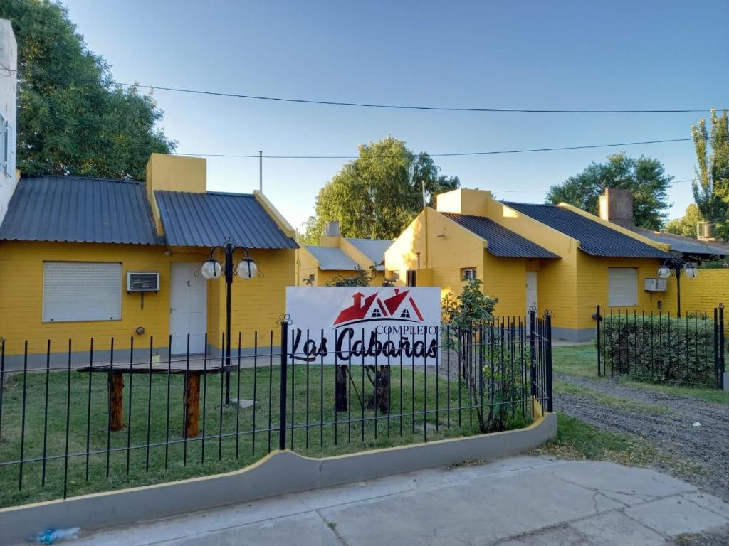 una casa amarilla con un cartel en una valla en Las Cabañas en Río Colorado
