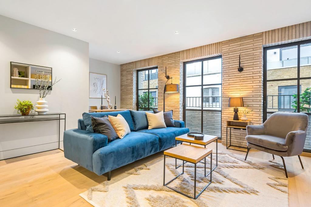 un soggiorno con divano blu e sedia di Be London - The Bloomsbury Residences a Londra
