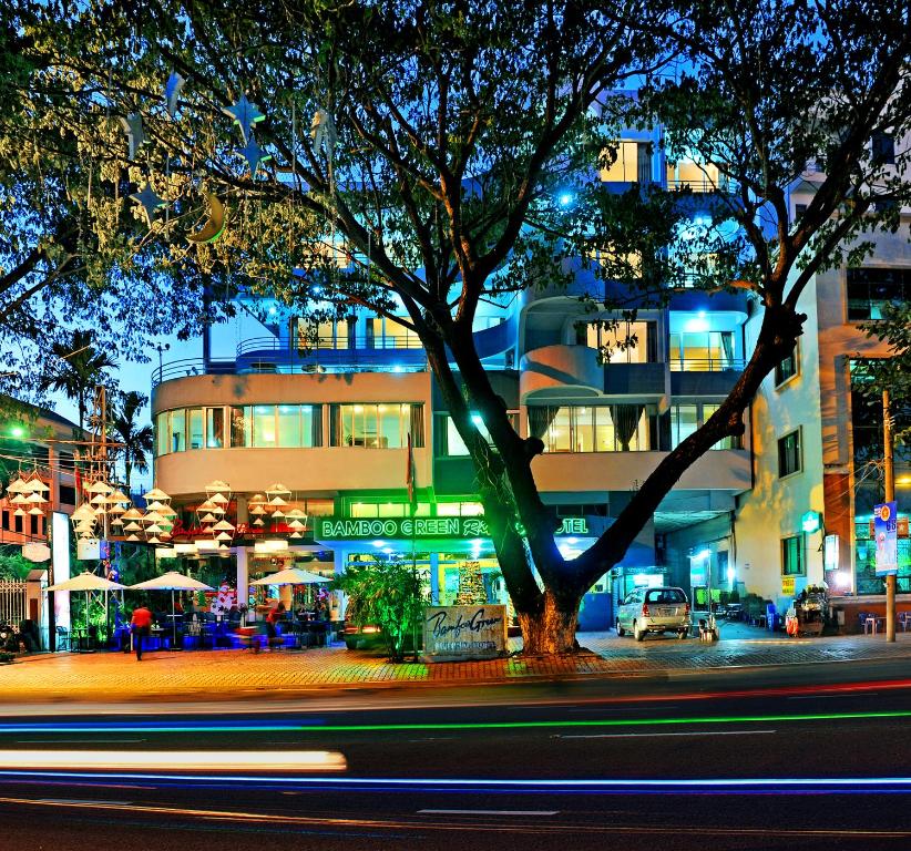 un árbol delante de un edificio por la noche en Bamboo Green Riverside Hotel, en Da Nang