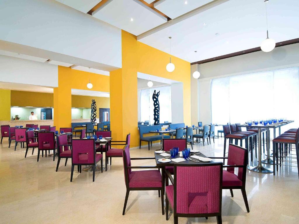 a dining room with tables and chairs in a restaurant at ibis Pune Viman Nagar - An Accor Brand in Pune