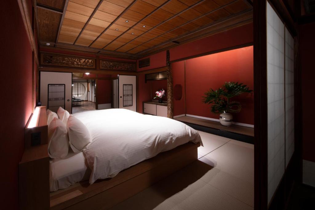 金沢市にあるHOTEL 101 KANAZAWAの白いベッドと赤い壁のベッドルーム1室
