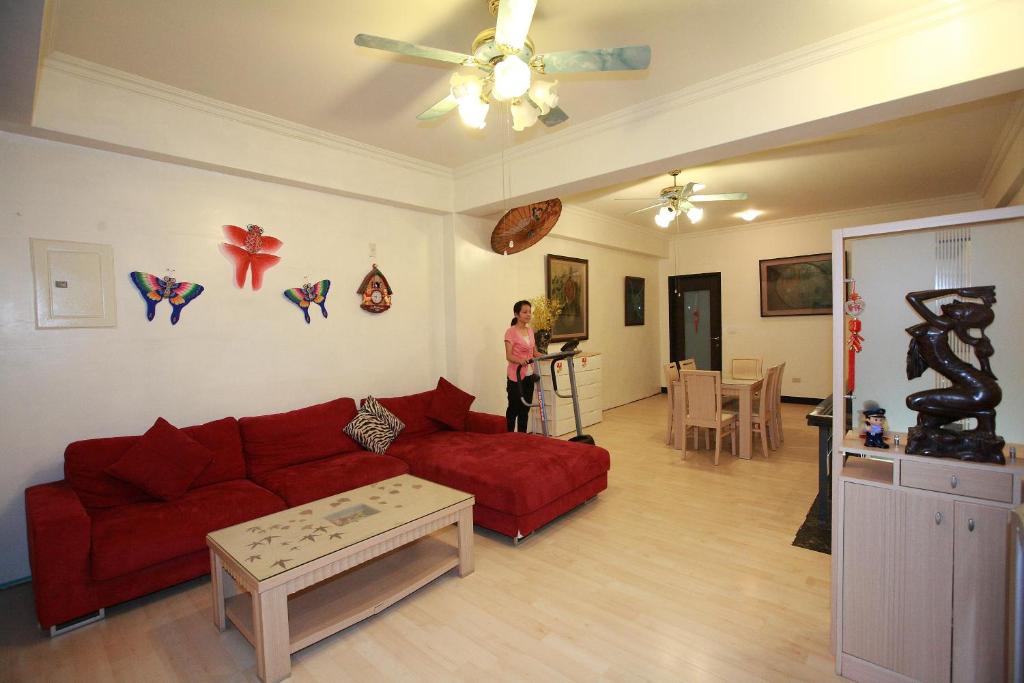 a woman standing in a living room with a red couch at Cruise Homestay in Hualien City