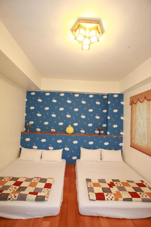 two beds in a room with a blue wall at Cruise Homestay in Hualien City