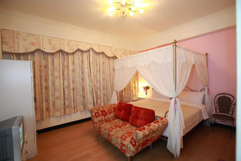 a bedroom with a canopy bed and a couch at Cruise Homestay in Hualien City