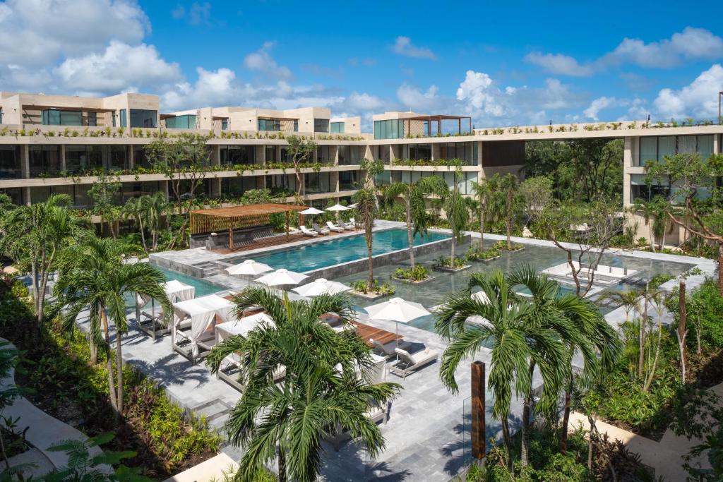un complejo con piscina y palmeras en MISTIQ Tulum Luxury Apartments, en Tulum