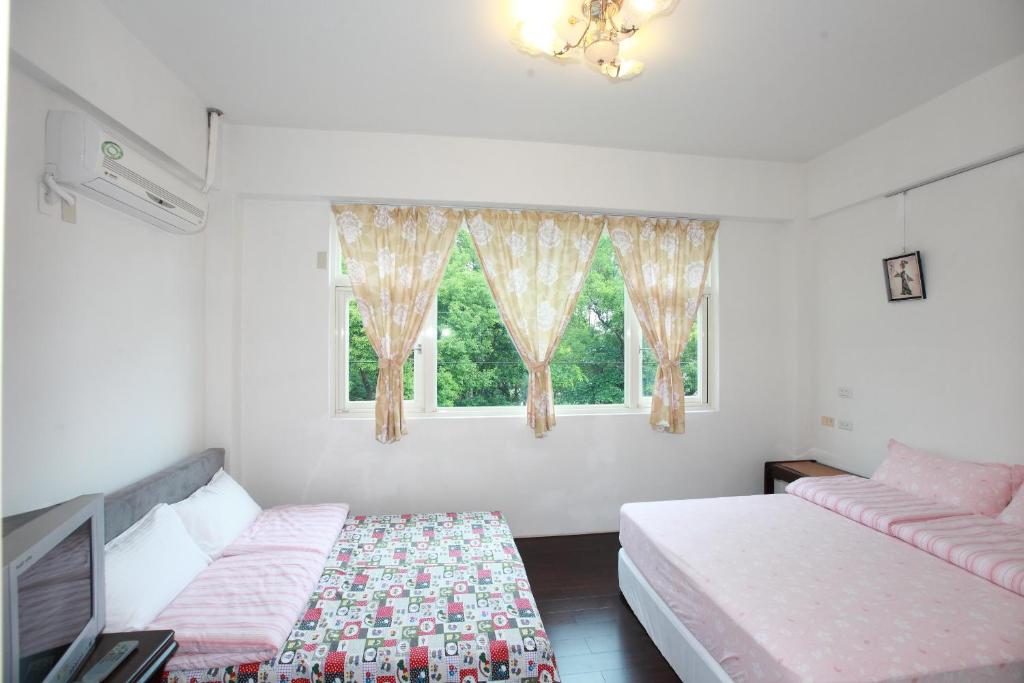 1 dormitorio con 2 camas y ventana en Travelers Fu-Home, en Hualien City