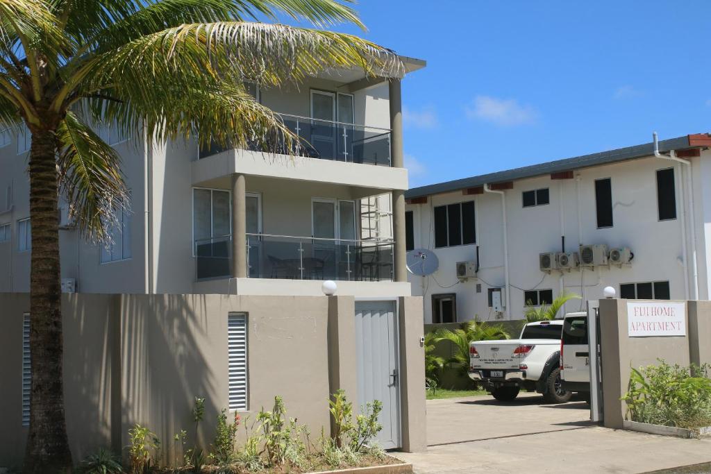 ein Gebäude mit einer Palme neben einem Parkplatz in der Unterkunft FIJI HOME Apartment Hotel in Suva