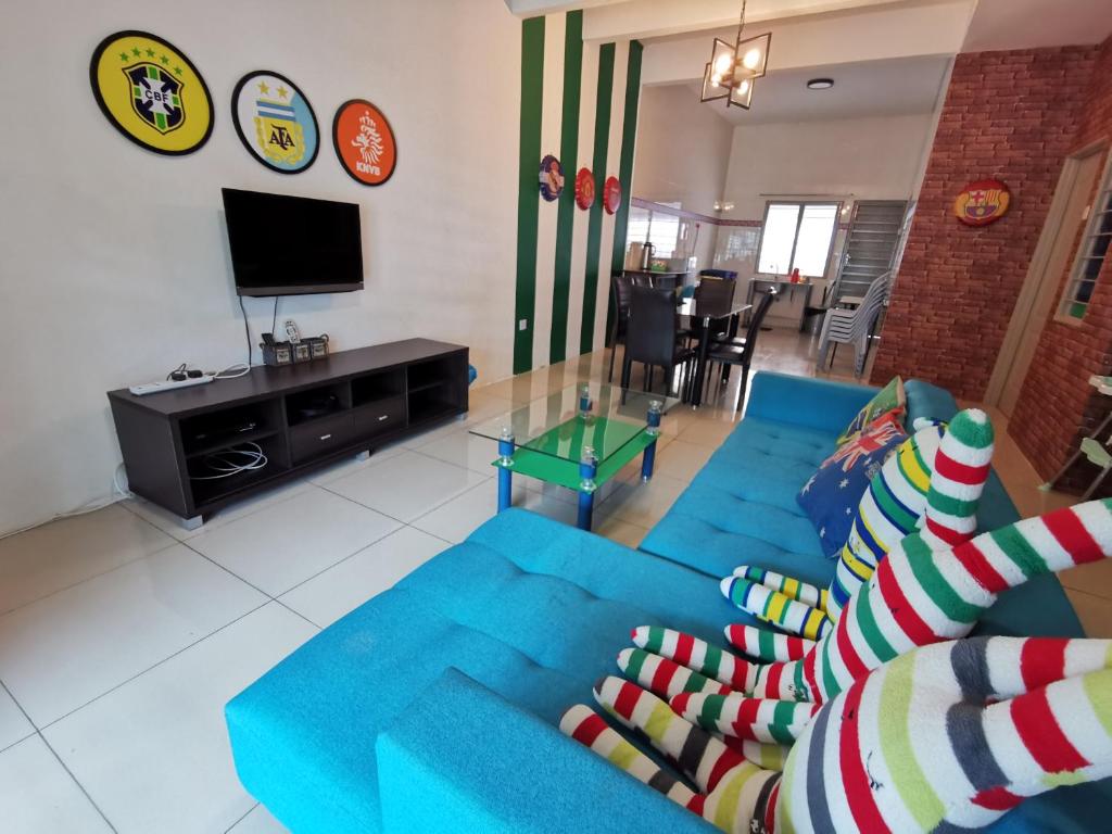a living room with a blue couch and a tv at The Woodz Homestay - 2 Storey Landed House in Cameron Highlands