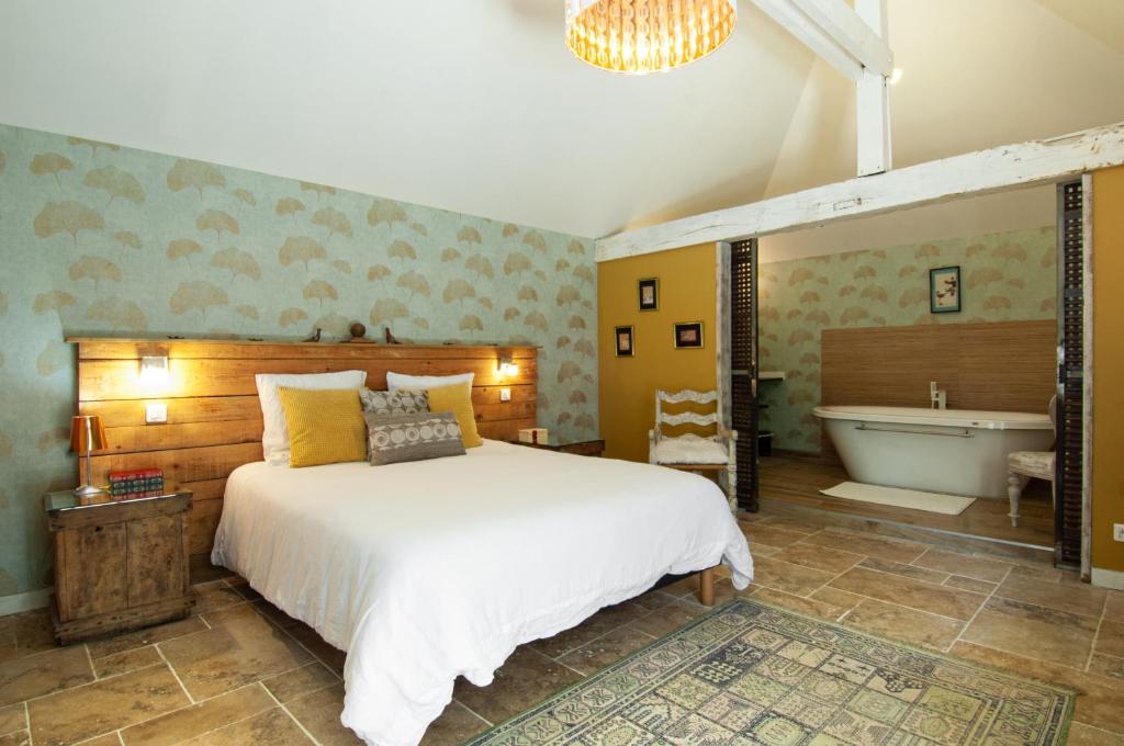 a bedroom with a large bed and a bath tub at Domaine du Lieu des Brocs - Country Club in Brucourt