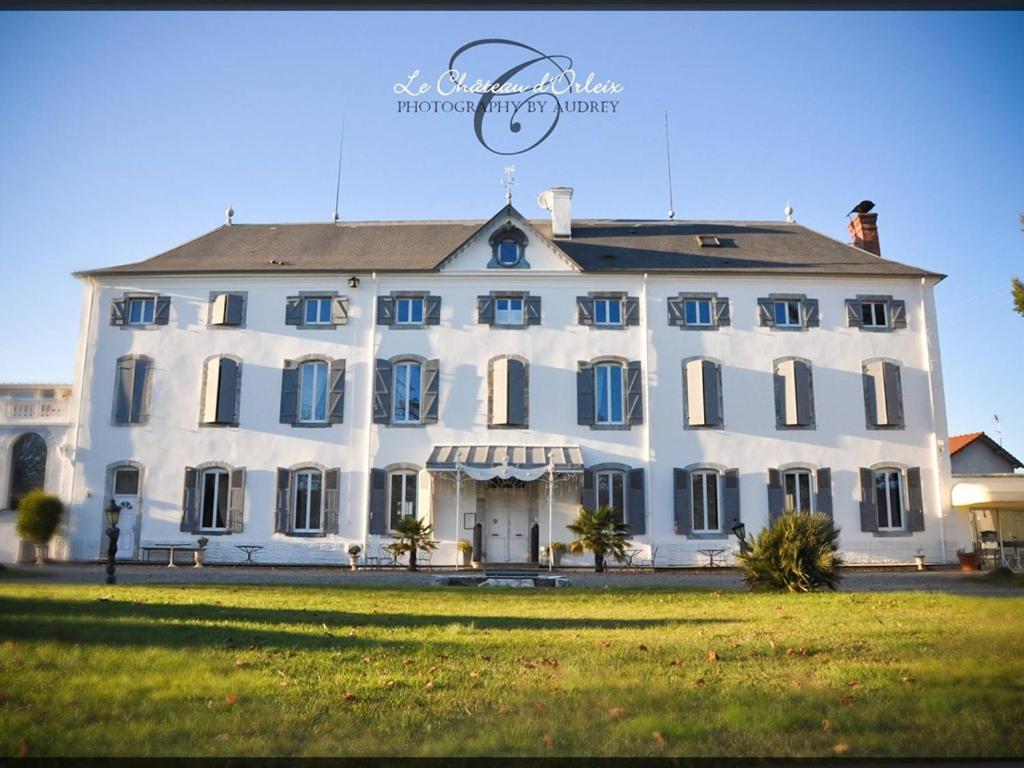 ein großes weißes Gebäude mit einer Uhr darüber in der Unterkunft Le Château d'Orleix in Orleix