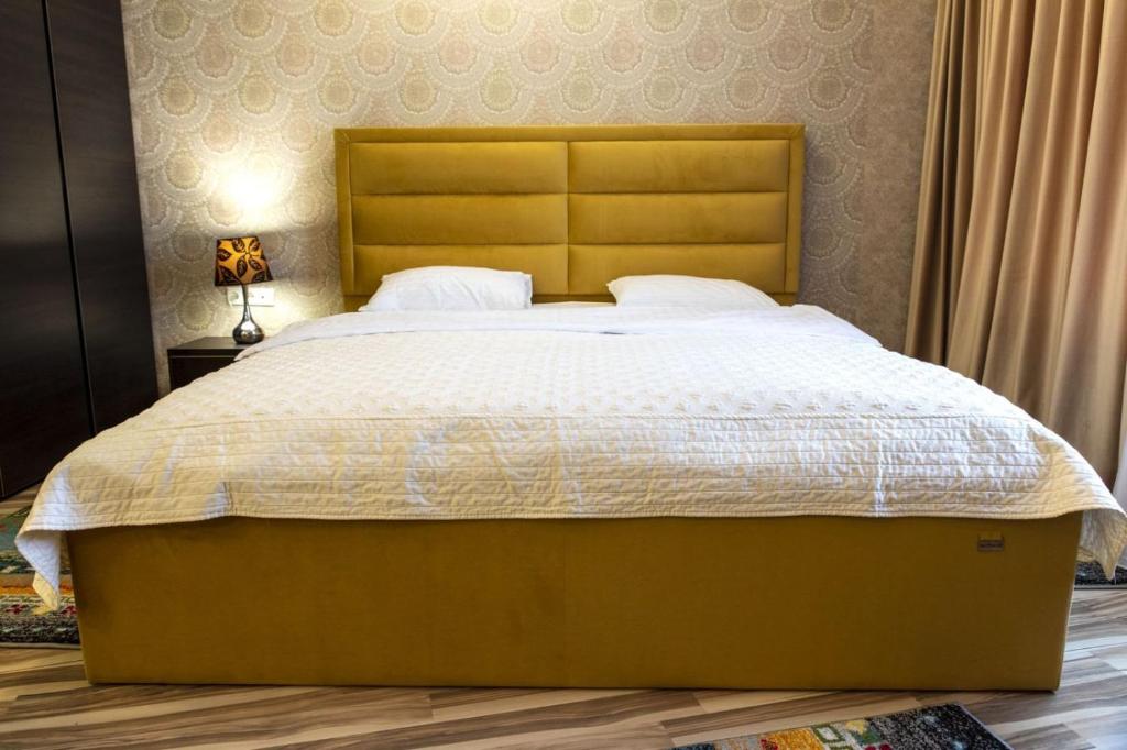 a bedroom with a large bed with a wooden headboard at Seven Eleven Apartment HOTEL in Most City in Dnipro
