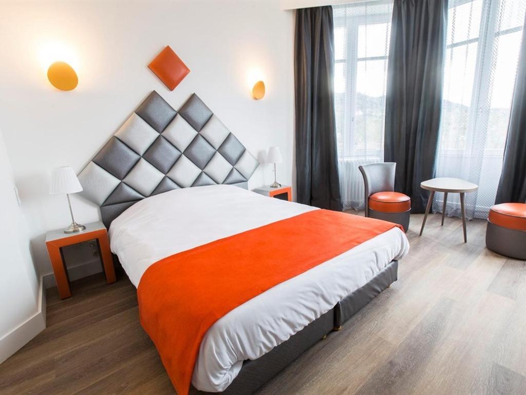 ein Schlafzimmer mit einem großen Bett mit einer orangefarbenen Decke in der Unterkunft Villa Fani in Thiers