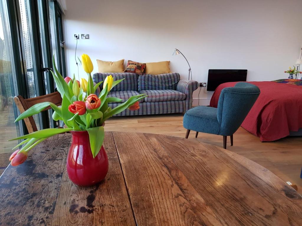 a red vase with flowers on a wooden table in a living room at The Sett on The Wharfe in Threshfield
