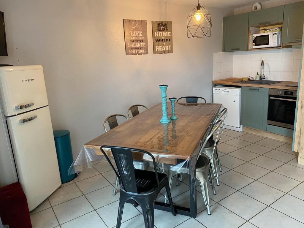 een keuken met een houten tafel met stoelen en een koelkast bij appartement au pied des pistes in La Chal