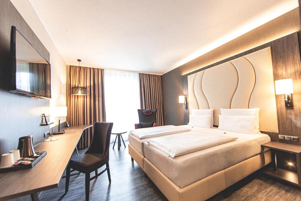 um quarto de hotel com uma cama e uma secretária em PLAZA Premium Parkhotel Norderstedt em Norderstedt