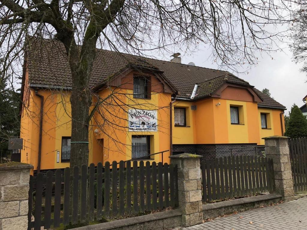 una casa amarilla con una valla delante de ella en Penzion Borováček en Borová Lada