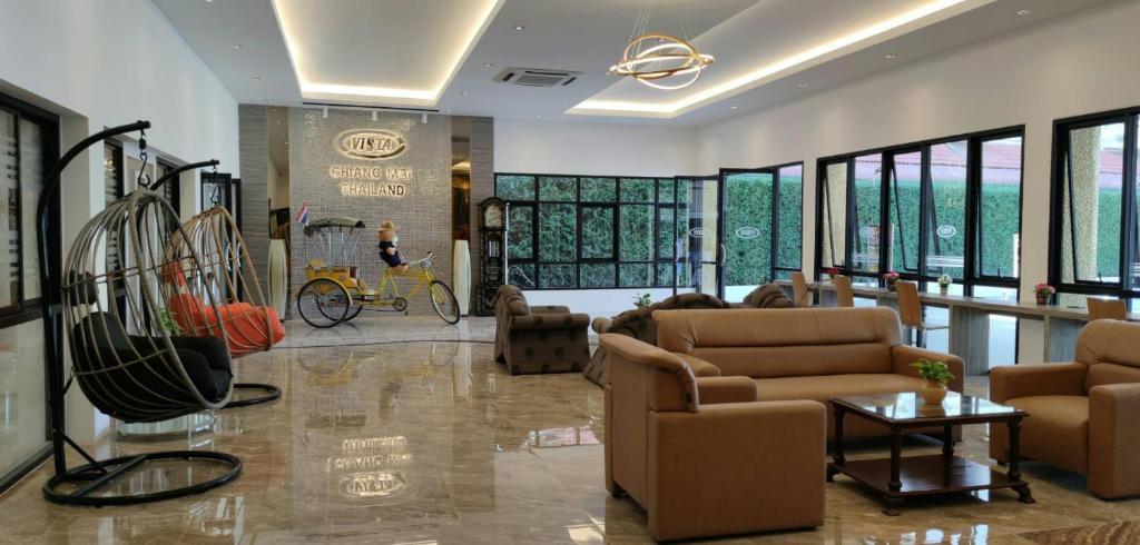 A bright lobby lounge with sofas, hanging chairs, bicycles, and tall windows.