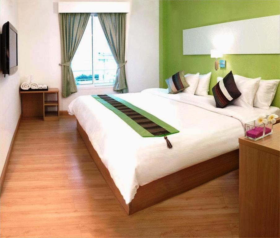 a large white bed in a room with a window at Nantra de Comfort in Bangkok