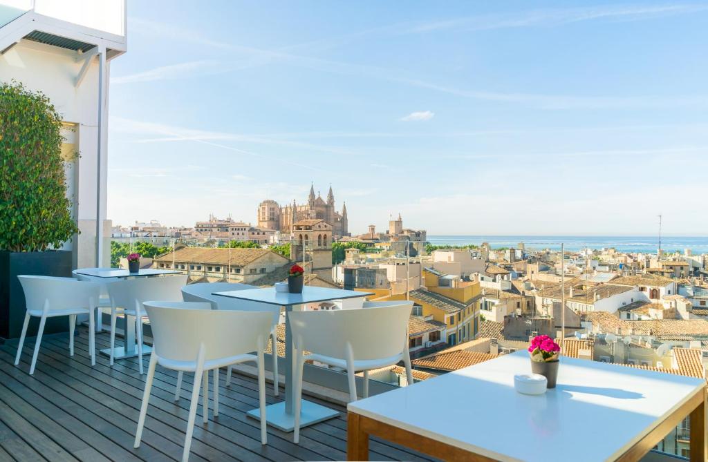 uma varanda com mesas e cadeiras e vista para a cidade em Hotel Almudaina em Palma de Maiorca