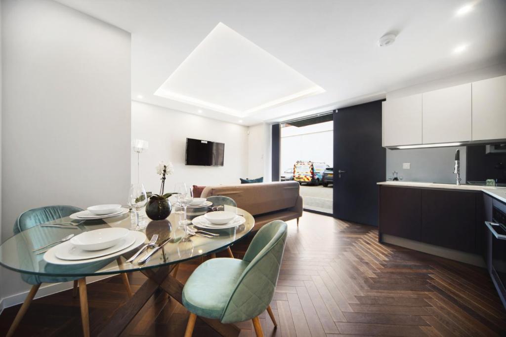 a kitchen and dining room with a glass table and chairs at Lux Apartments in Fulham in London