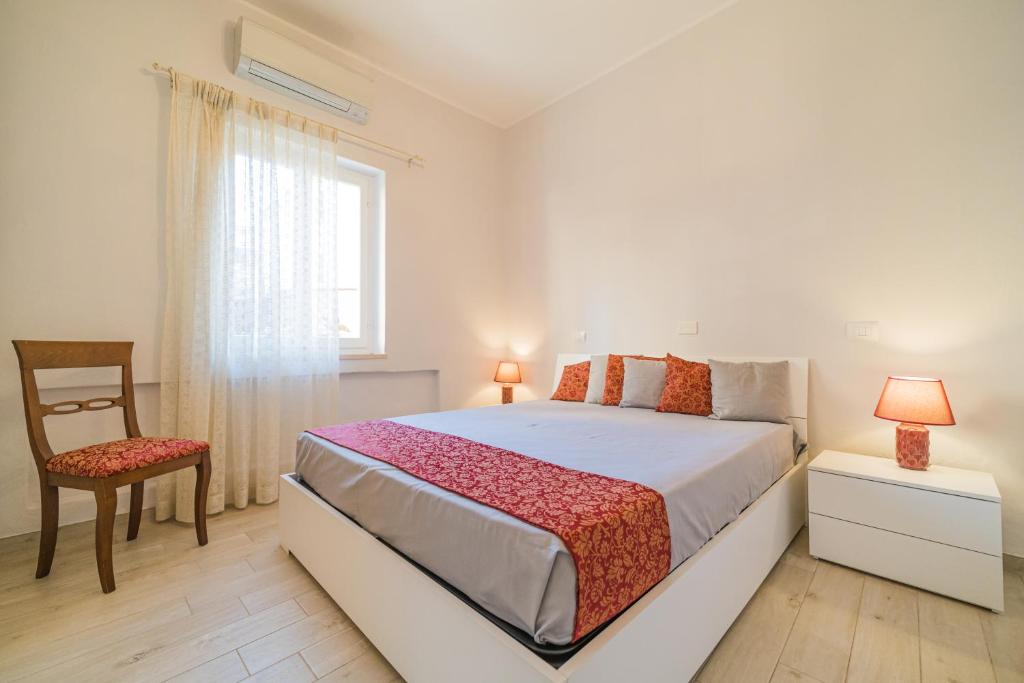 sypialnia z łóżkiem, krzesłem i oknem w obiekcie Suite Alarcon w mieście Porto Azzurro
