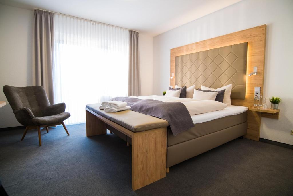 ein Schlafzimmer mit einem Bett, einem Stuhl und einem Fenster in der Unterkunft Hagen`s Hotel "eat & meet" Restaurant Bar Lounge in Haren