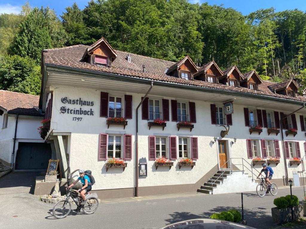zwei Personen, die vor einem Gebäude Fahrrad fahren in der Unterkunft Historic Hotel Steinbock in Wilderswil