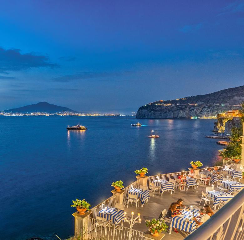 a view of the ocean from a balcony with tables and chairs at Grand Hotel Riviera in Sorrento