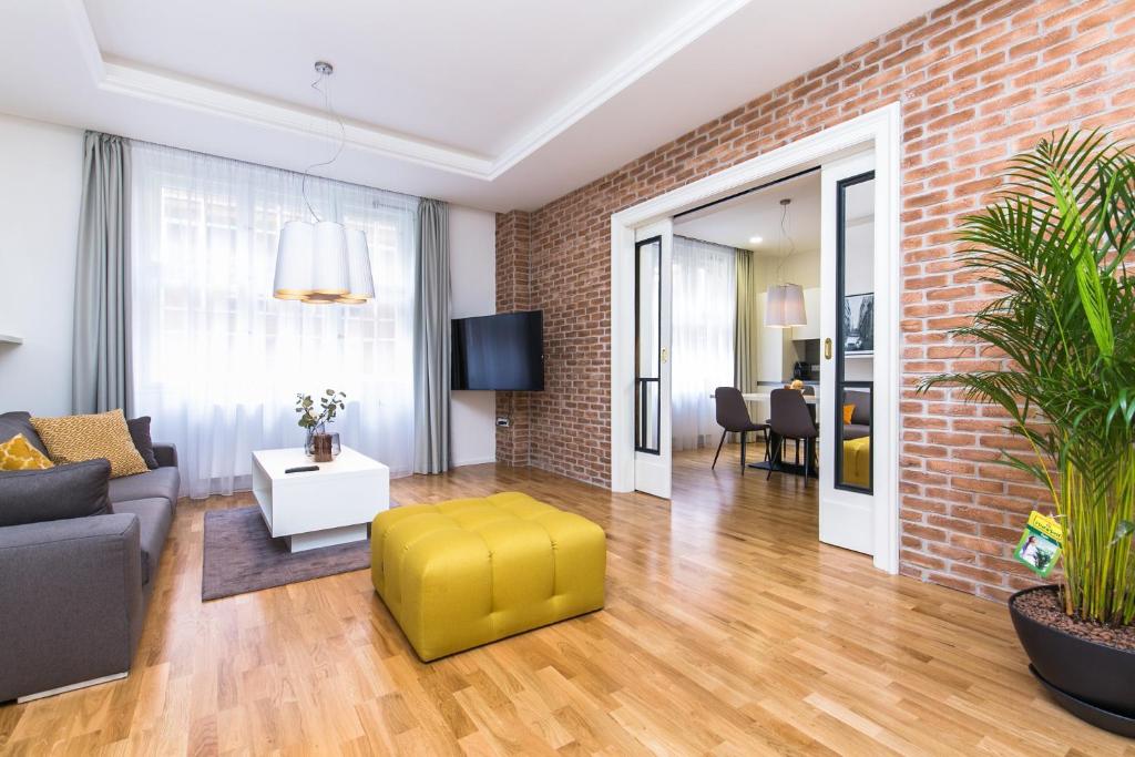 a living room with a couch and a yellow stool at UNIQUE Old Town apartments at Palace Dlouha in Prague