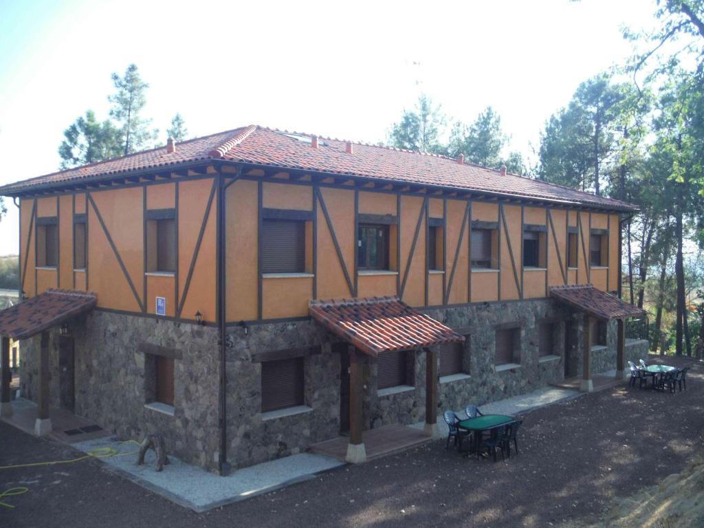 un grand bâtiment avec des tables et des chaises devant lui dans l'établissement El Rincón de los Riveros, à El Raso