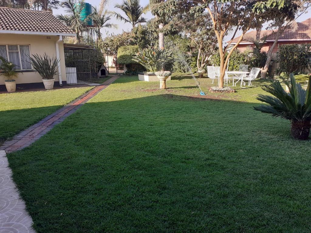 un patio con césped verde y una casa en Beautiful 2-Bedroomed Guest Cottage in Harare en Harare