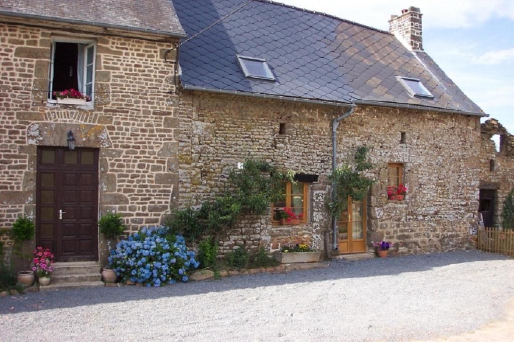 ein Steinhaus mit Blumen davor in der Unterkunft Beautiful 3-Bed Cottage in Passais-Villages in Saint-Siméon