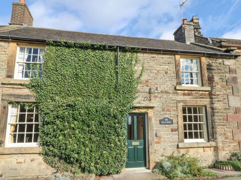 an ivy covered house with a green door at Beautiful 3-Bed House in Longnor near Buxton in Longnor
