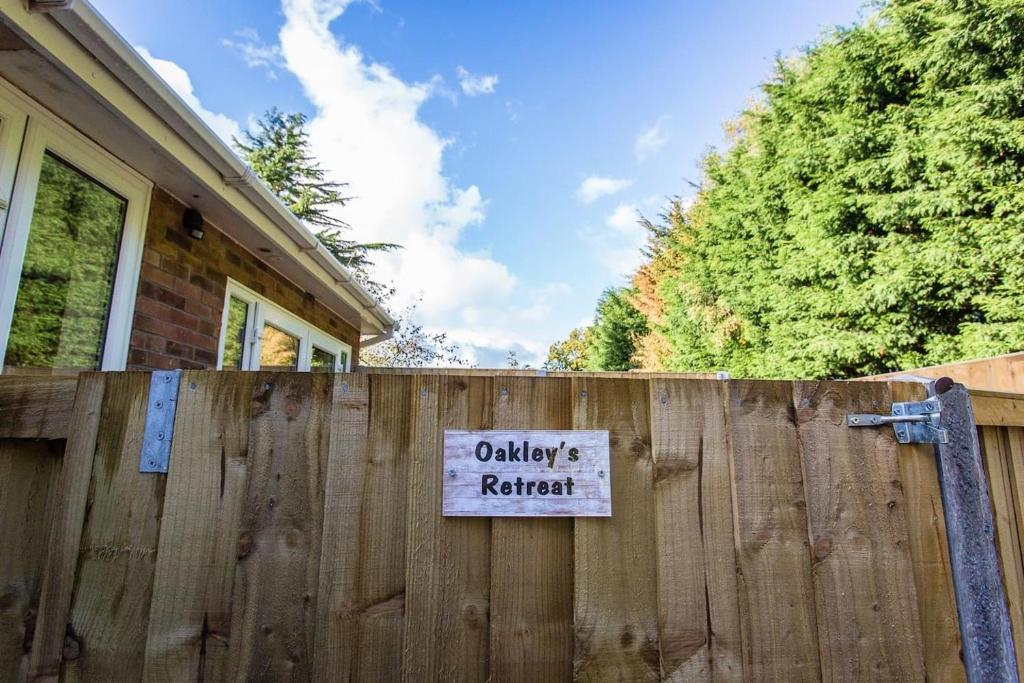 a sign on a wooden fence in front of a house at Oakley Retreat in Baddiley