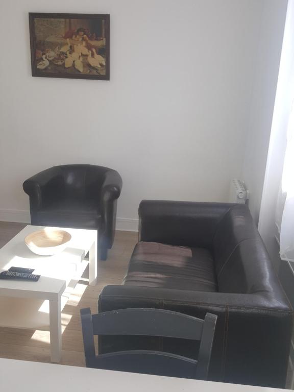 - un salon avec un canapé en cuir noir et une table dans l'établissement Respire le Bien-être, à Rosny-sous-Bois