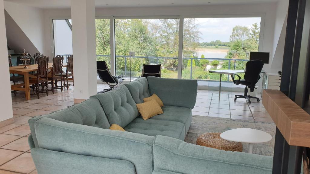 ein Wohnzimmer mit einem blauen Sofa und einem großen Fenster in der Unterkunft Somnar Panoramaloft mit Hästens Betten - Rheinblick 150qm in Neuss