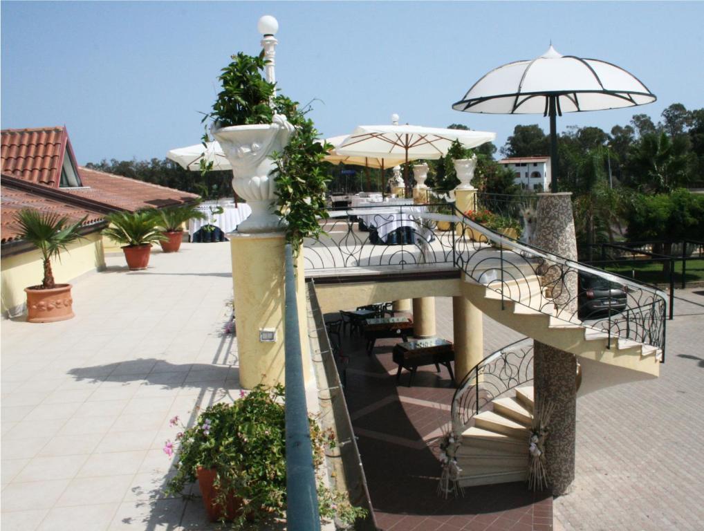 Un escalier mène à une terrasse avec une table et un parasol. dans l'établissement Hotel Miramare, à Marina di Schiavonea